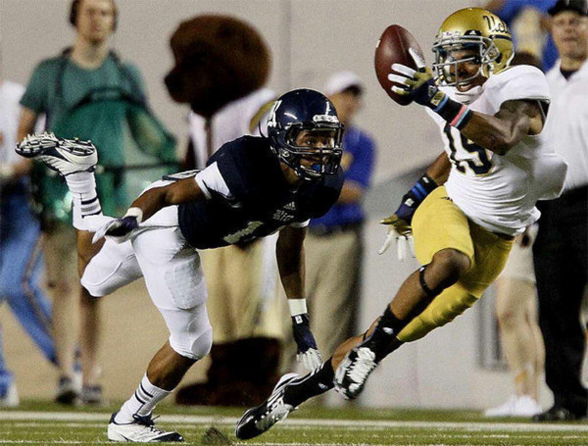 UCLA receiver Devin Lucien hauls in a long pass over Rice defender J.T. Blasingame.