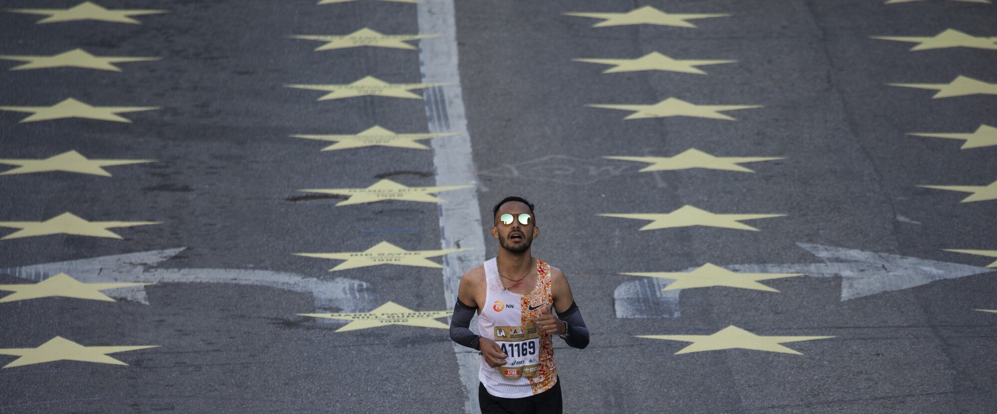 A runner crosses the finish line on Avenue of the Stars in Century City during the LA Marathon on Sunday