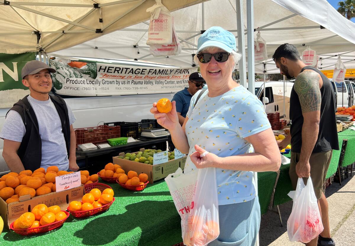 Patricia West bought fresh tangerines from Carmelo Martinez at the Heritage Family Farm booth.
