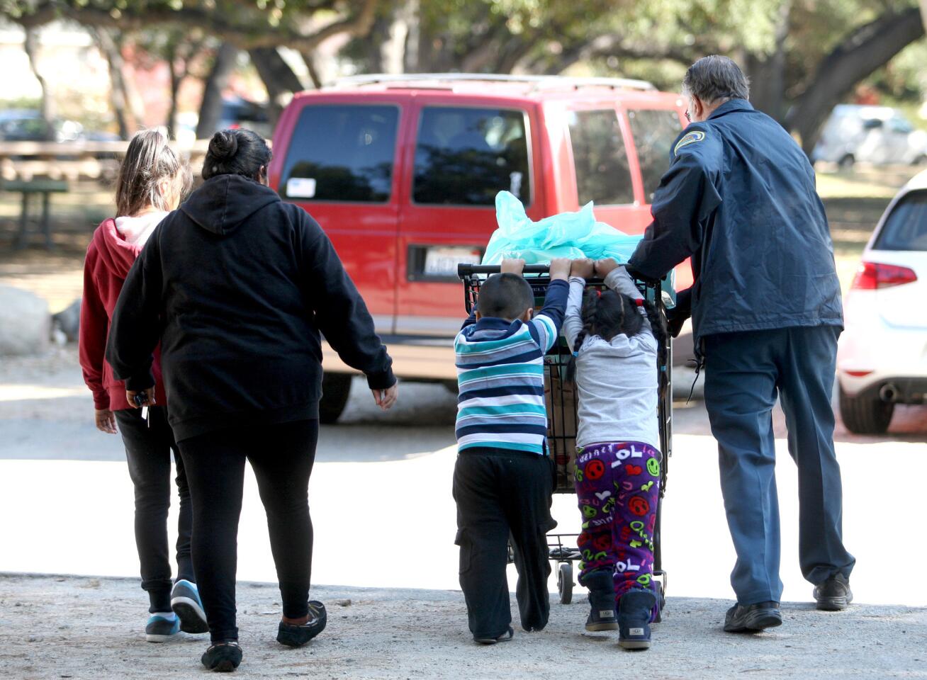 Los Angeles County Sheriff's Crescenta Valley Station volunteer Paul Graettinger, right, helps the Parra family to their car with a cart of groceries and toys during the Crescenta Valley Sheriff Station's annual Toy and Food Drive at Crescenta Valley Park in La Crescenta on Saturday, Dec. 19, 2015. Evelyn, 5, and Eliu, 4, help push the heavy cart.