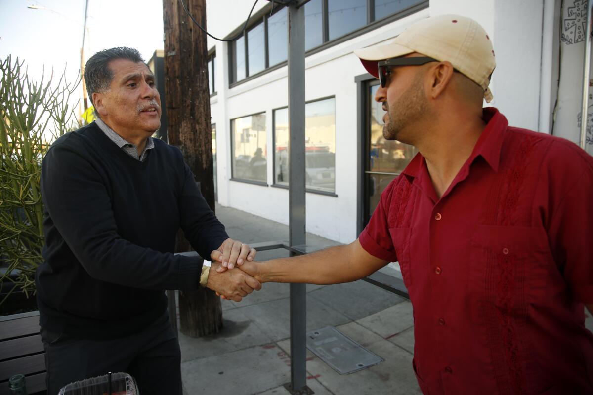 Robert Luna, left, shakes hands with a supporter in Long Beach.