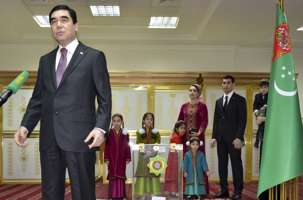FILE - Turkmenistan President Gurbanguly Berdimuhamedov, left, speaks to journalists after casting his ballot as his son Serdar Berdymukhamedov, second right, with other family members look on at a polling station in Ashgabat, Turkmenistan, Feb. 12, 2017. People of Turkmenistan cast ballots Saturday March 12, 2022 in a vote intended to lay the foundation for a political dynasty in the gas-rich Central Asian nation. President Gurbanguly Berdymukhamedov, 64, announced the vote last month, setting stage for his 40-year old son Serdar to take over. (AP Photo/Alexander Vershinin, File)