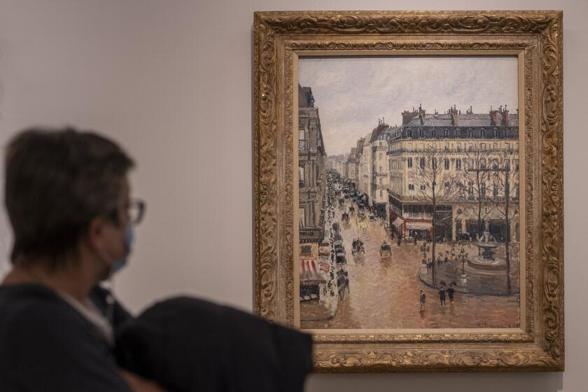 A woman looks at the Impressionist painting called "Rue St.-Honore, Apres-Midi, Effet de Pluie" painted in 1897 by Camille Pissarro, on display at the Thyssen-Bornemisza Museum in Madrid, Spain, Friday, April 22, 2022. A leading Spanish museum the Thyssen-Bornemisza says it's confident U.S. courts will again rule that the valuable French painting taken from a Jewish family by the Nazis belongs to the museum and not to the family's descendants. Spain's Thyssen-Bornemisza National Museum says Friday that, despite a new U.S. Supreme Court ruling that returns the case to lower courts, it was sure those courts would once again rule that Spanish law, rather than California law, should prevail. (AP Photo/Manu Fernandez)