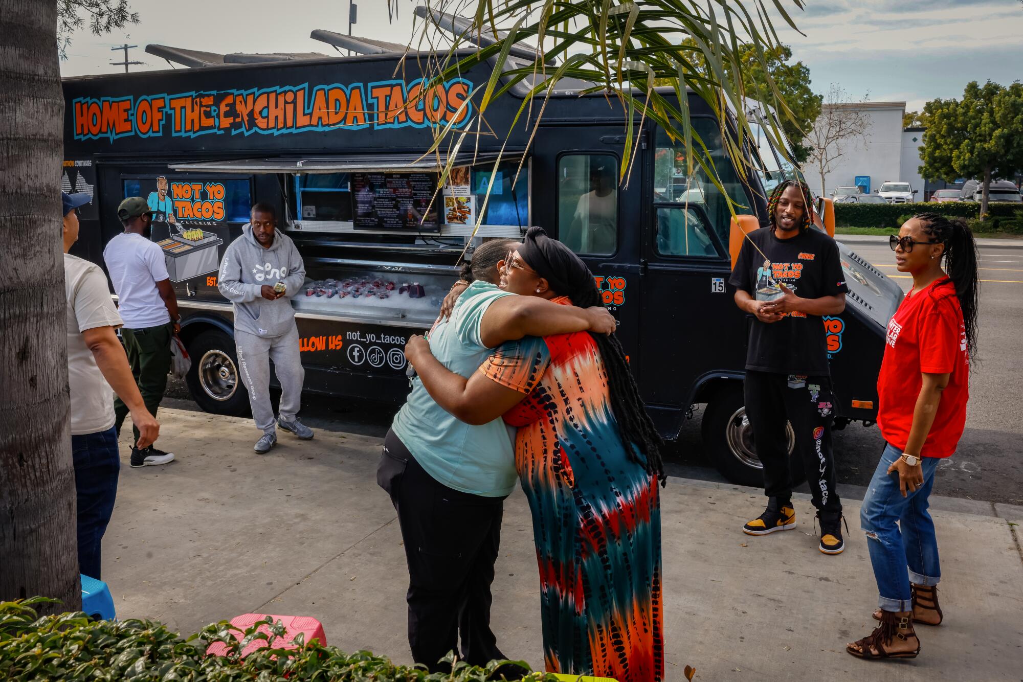 People hug and stand in front of the Not Yo Tacos truck.