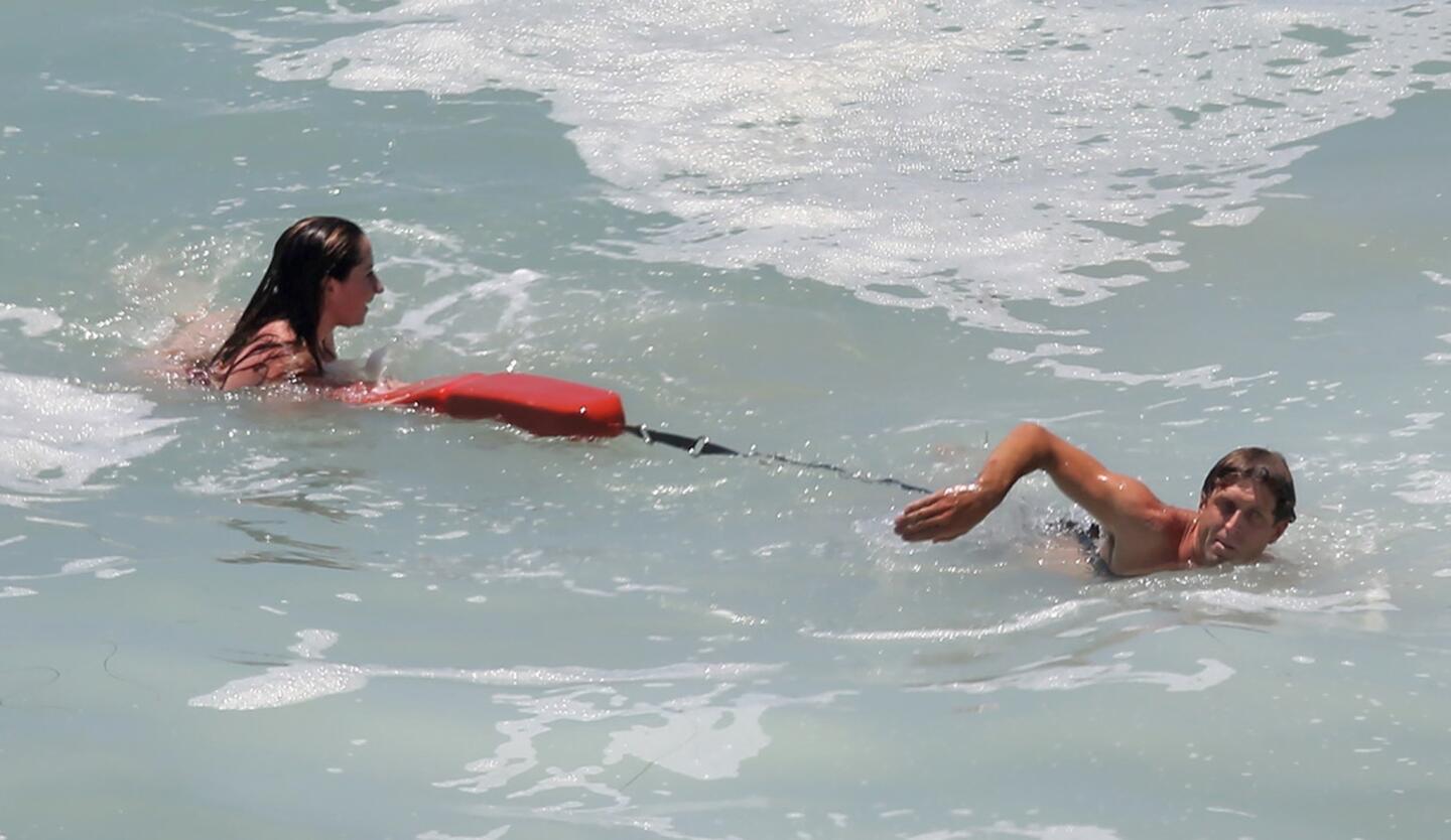 A Laguna Beach lifeguard helps a swimmer back to shore after large waves and strong rip currents pulled her out to sea south of the Montage resort on Monday.