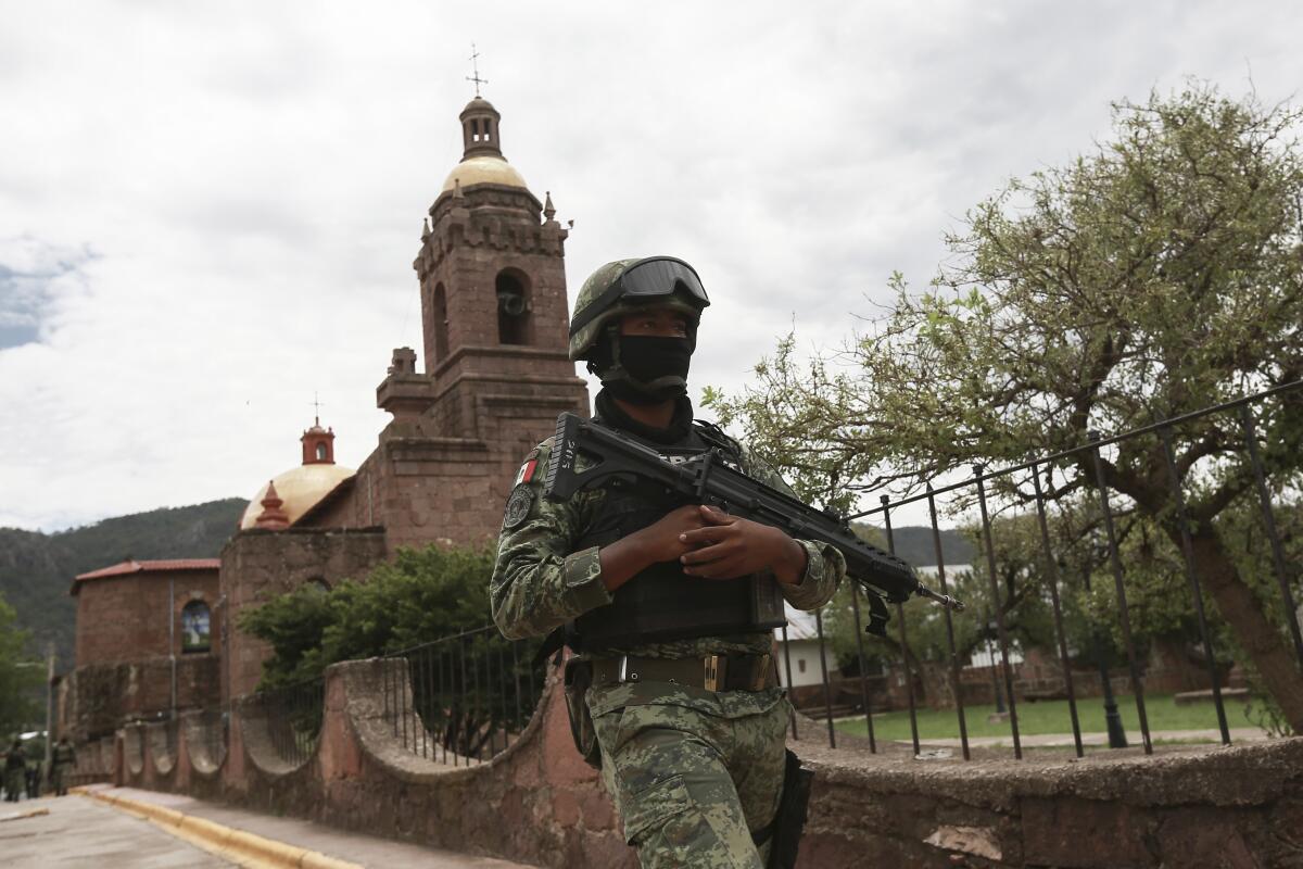 A Mexican soldier patrols outside the Church in Cerocahui, Mexico, Wednesday, June 22, 2022. Two elderly Jesuit priests were killed inside the church where a man pursued by gunmen apparently sought refuge, the religious order´s Mexican branch announced Tuesday. (AP Photo/Christian Chavez)