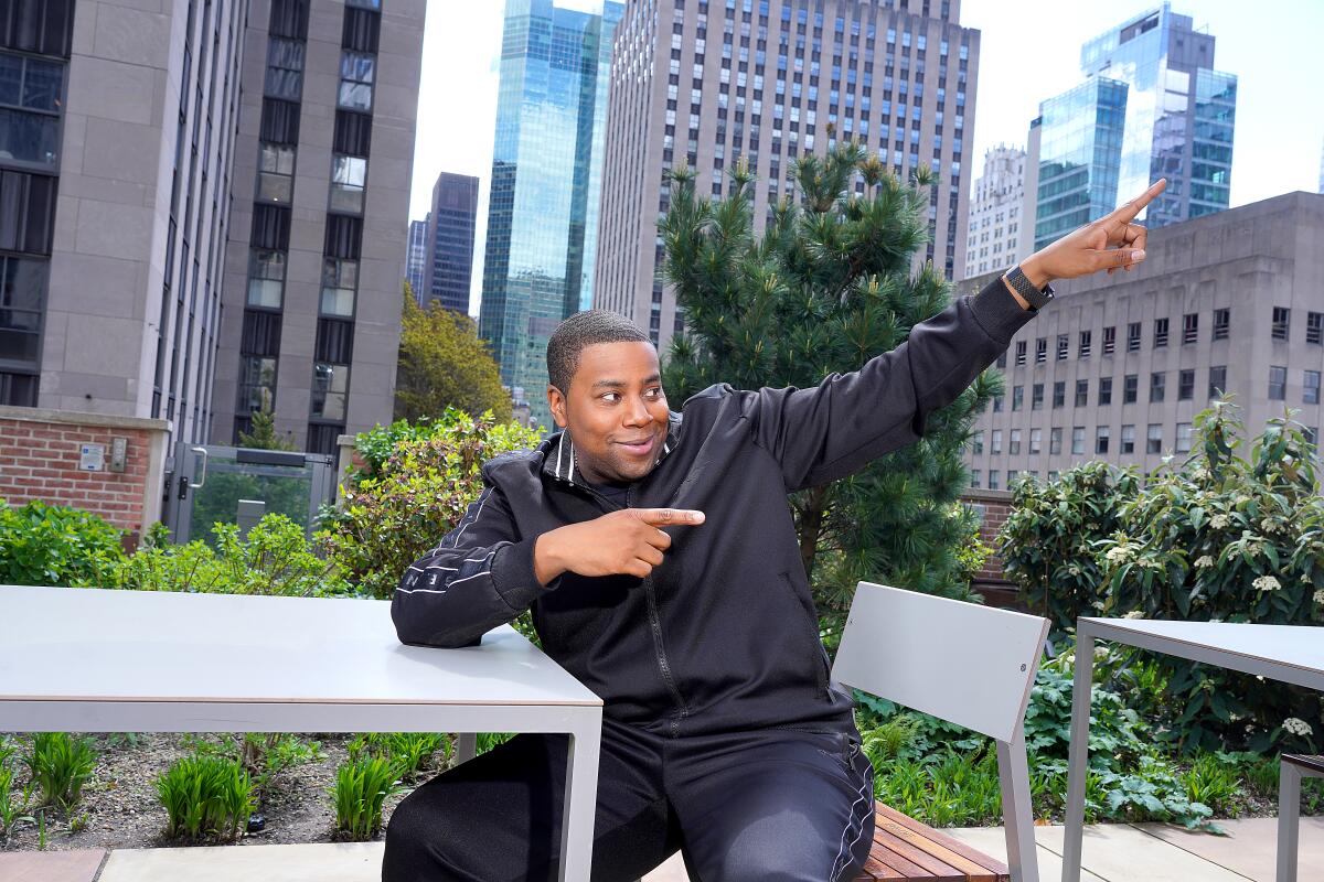 A man sitting and pointing at the sky with skyscrapers in the background