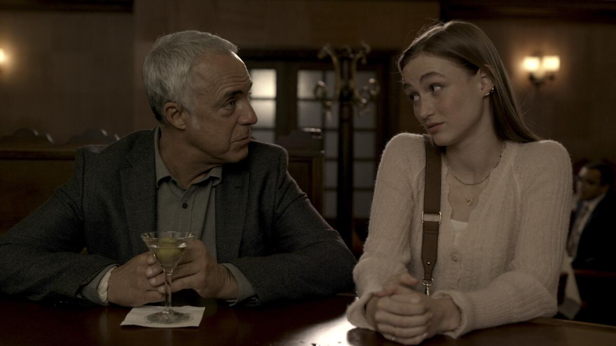 A man drinking a martini at a bar while his adult daughter looks on