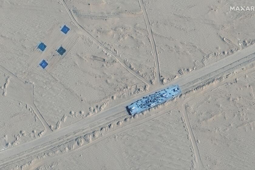 This satellite image provided by Maxar Technologies shows a building on rail tracks in Ruoqiang county, China, Wednesday, Oct. 20, 2021. Satellite images appear to show China has built mock-ups of U.S. Navy aircraft carriers and destroyers in its northwestern desert, such as one at center in this image, possibly as practice for a future naval clash as tensions rise between the nations. (Maxar Technologies via AP)