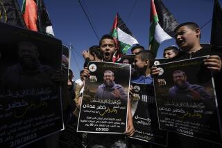 Palestinian kids wave their national flag and hold posters showing Khader Adnan, a Palestinian Islamic Jihad militant who died in Israeli prison after a nearly three-month hunger strike, in the West Bank village of Arrabe, near Jenin, Tuesday, May 2, 2023. Adnan began his strike shortly after being arrested on Feb. 5. Adnan, a leader in the Islamic Jihad militant group, had gone on hunger strikes several times after previous arrests. Arabic on poster reads "The Islamic Jihad in Palestine mourns the beloved leader Khader Adnan. The martyr of dignity, who died while he was engaged in a respectful strike in his empty stomach after a hunger strike that lasted 86 days." (AP Photo/Majdi Mohammed)