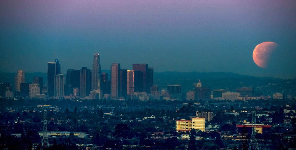 A rare super blue blood moon sets behind downtown skyscrapers in 2018.