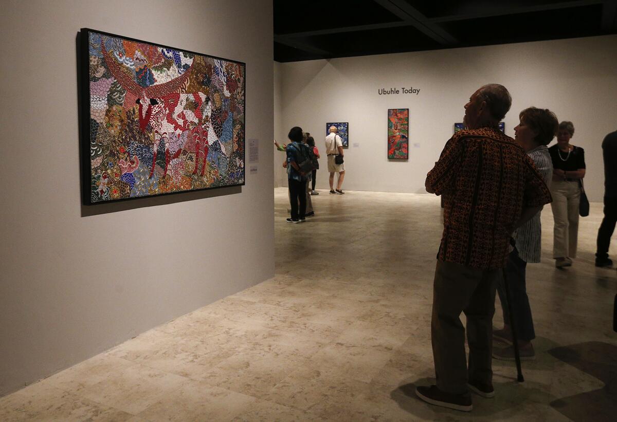 Guests admire "Dressed for the Dance," by Zondlile Zondo at the Bowers Museum.