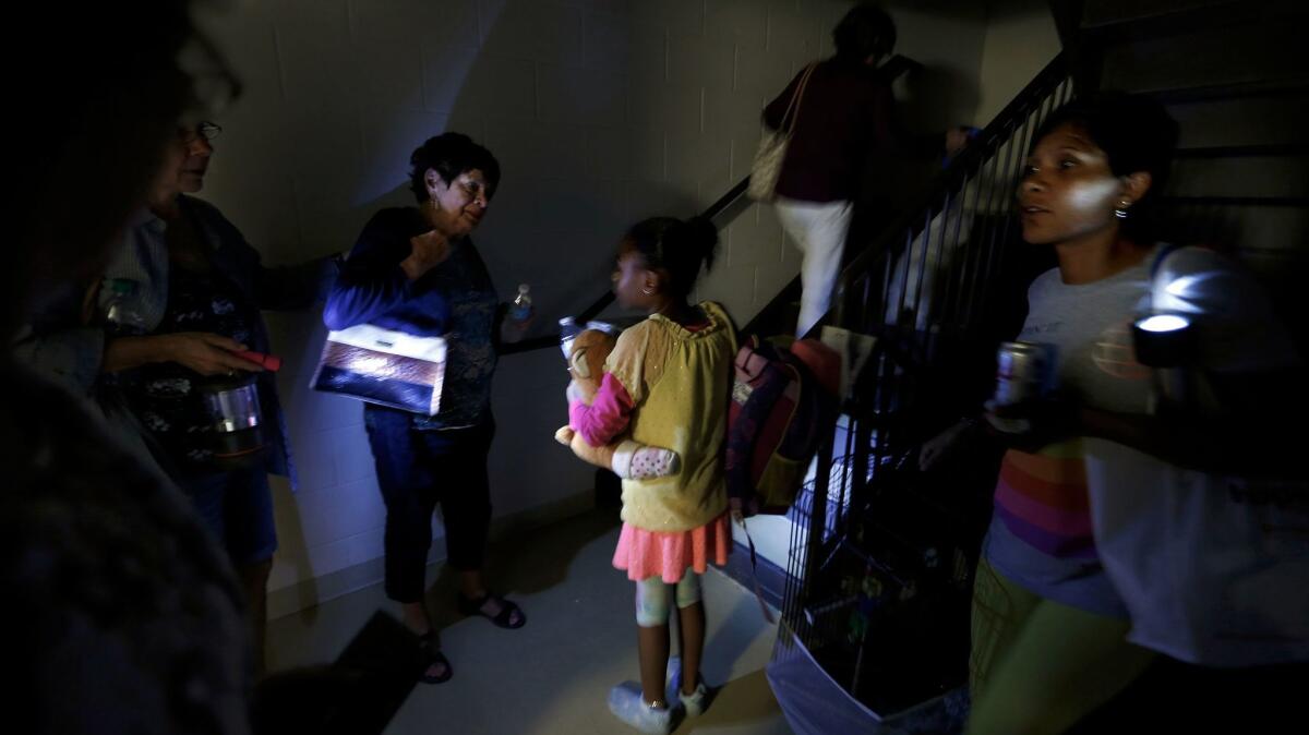 With the lights out at the Hampton Inn and Suites in Estero, Fla., the evacuees help one another make their way to the stairway with flashlights.