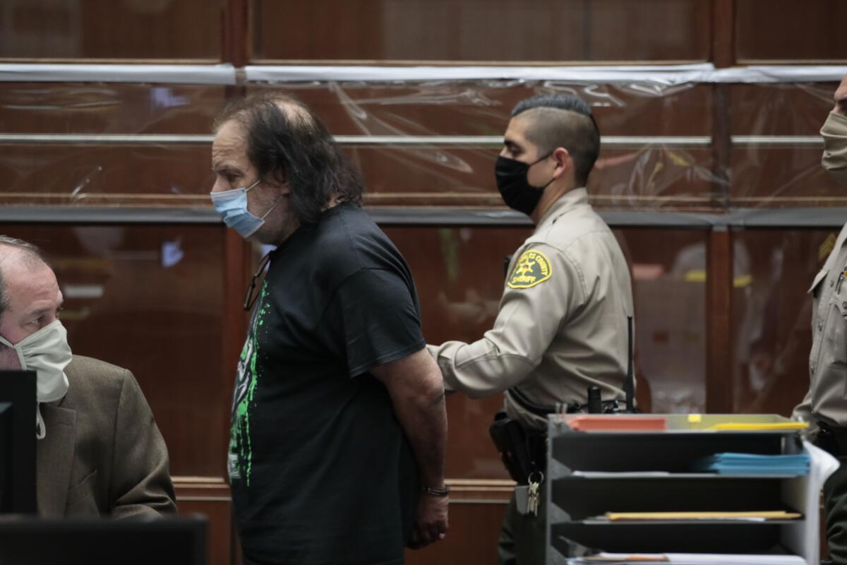 Adult film star Ron Jeremy, charged with four counts of sexual assault, leaves a Los Angeles County courtroom in handcuffs 