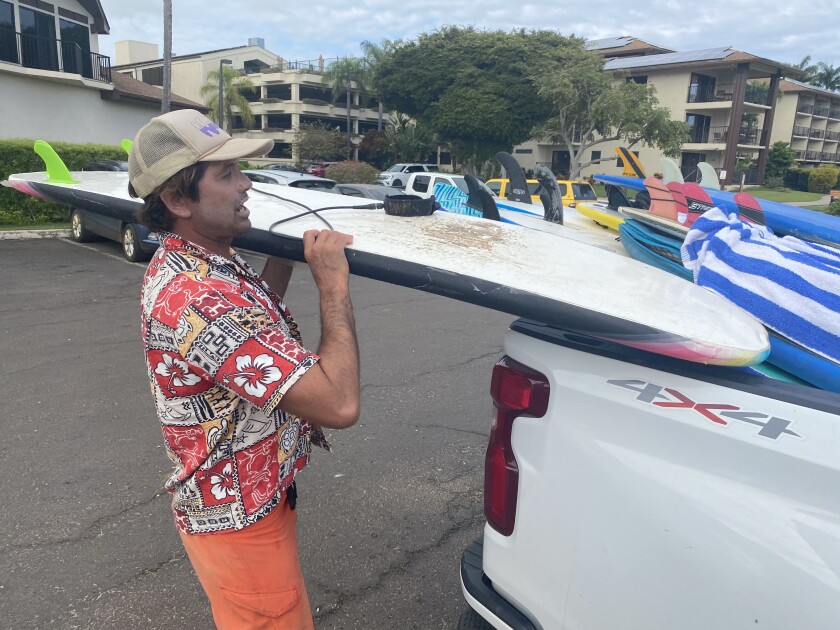 Kelley Hunt loads a surfboard into the back of a pickup.