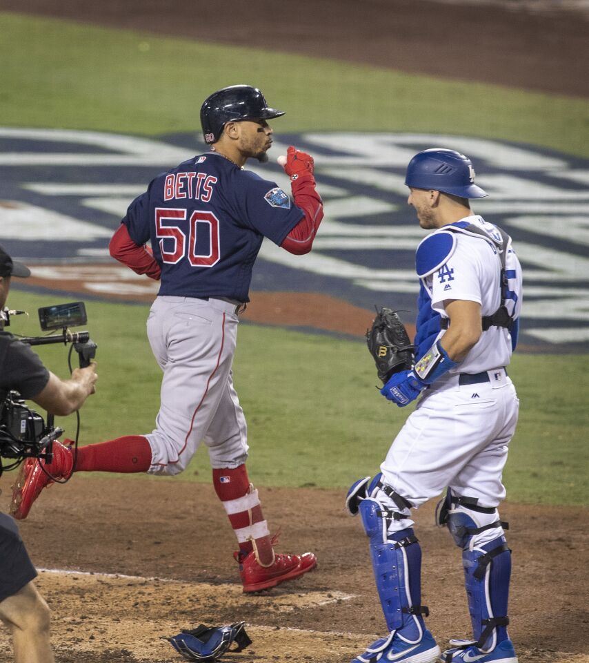 Dodgers catcher Austin Barnes looks away as Red Sox center fielder Mookie Betts celebrates after crossing home plate during his home-run trot in the sixth inning.