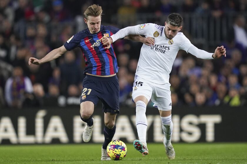 Barcelona's Frenkie de Jong, left, battles for the ball with Real Madrid's Federico Valverde, right, during the Spanish La Liga soccer match between Barcelona and Real Madrid at Camp Nou stadium in Barcelona, Spain, Sunday, March 19, 2023. (AP Photo/Joan Mateu)