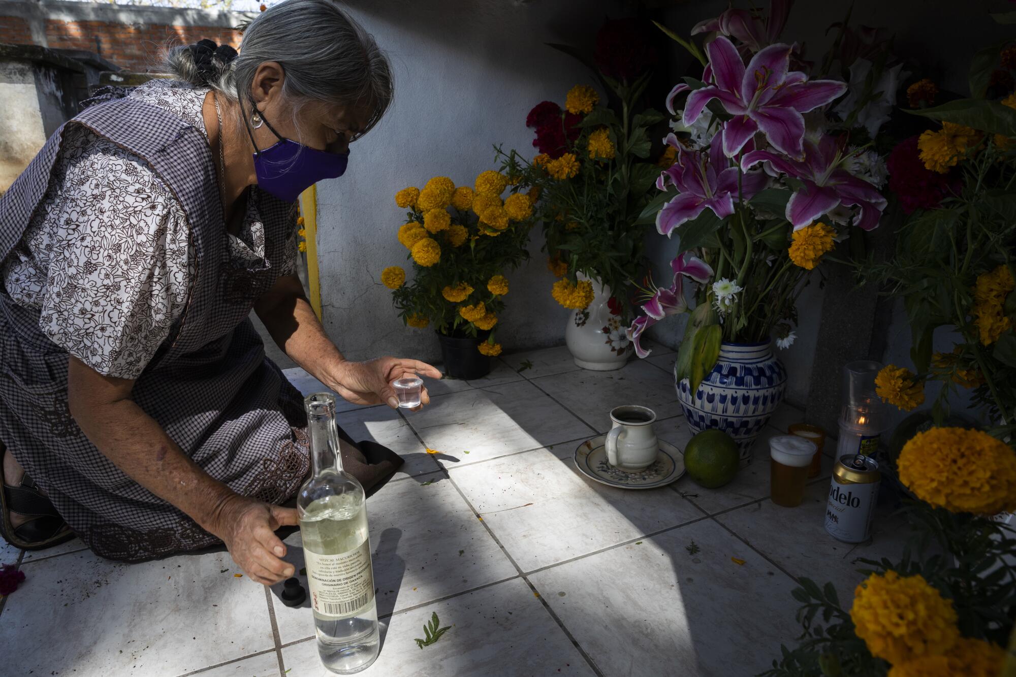 A woman kneels before an altar 