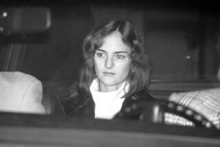 An unsmiling Patty Hearst is seated in a U.S. Marshal’s car, leaving the Sam Mateo County jail in Redwood City, Calif., Thursday, Dec. 12, 1975, on her way to San Francisco to an appearance in federal court. The odd cast in her eyes is caused by the flash bouncing back. (AP Photo/Sal Veder)