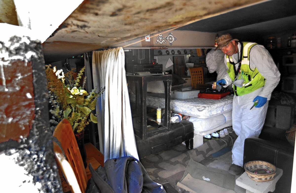 A city sanitation worker clears a living space under a pedestrian bridge over the Arroyo Seco during a sweep of homeless camps in northeast Los Angeles.