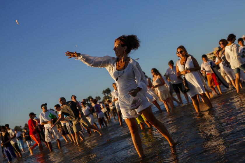 A woman throws a piece of bread into the ocean in celebration of Tashlich at Venice Beach on the first day of Rosh Hashanah. In the Jewish faith, Tashlich, which means "casting away," invites participants to throw bread into a flowing body of water to symbolically cast away their sins.