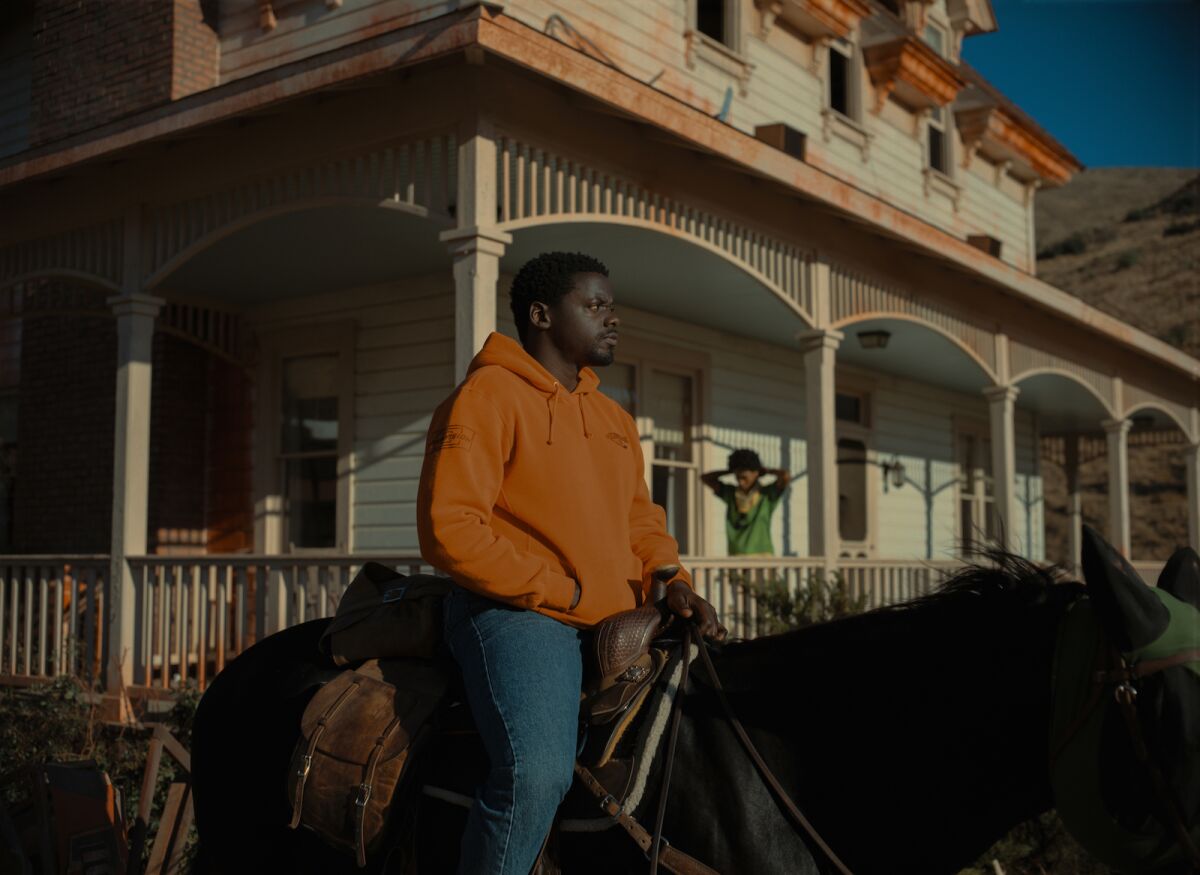 Daniel Kaluuya sits on a horse in front of a house where Keke Palmer stands on the porch in the movie "Nope."