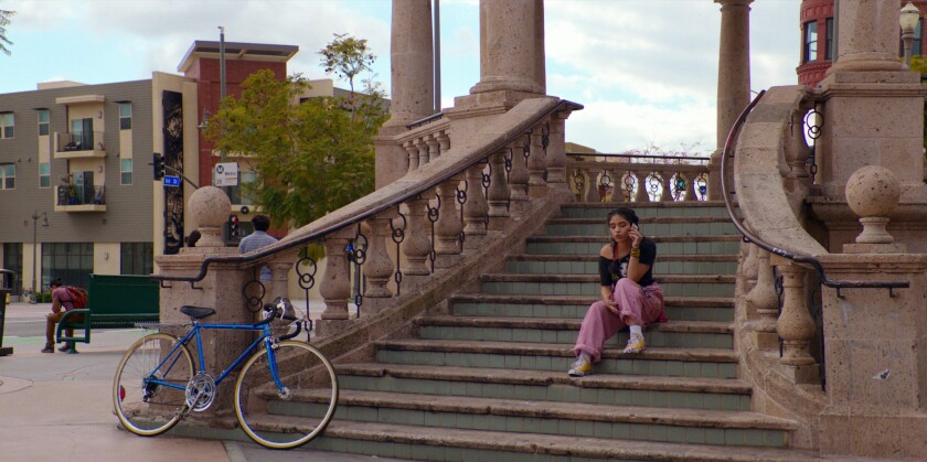 A young woman sits on the steps at Mariachi Plaza.