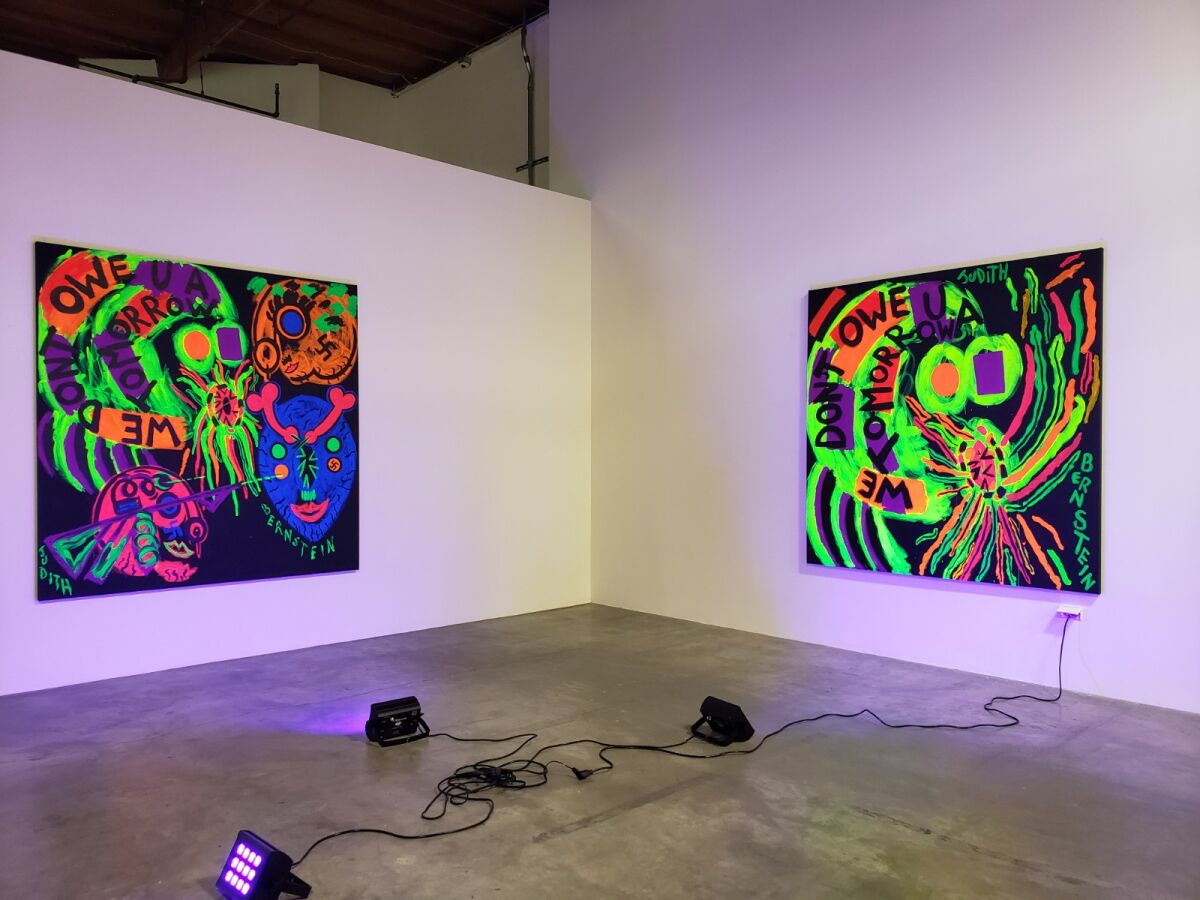 Black lights illuminate two bright photos against two white walls.