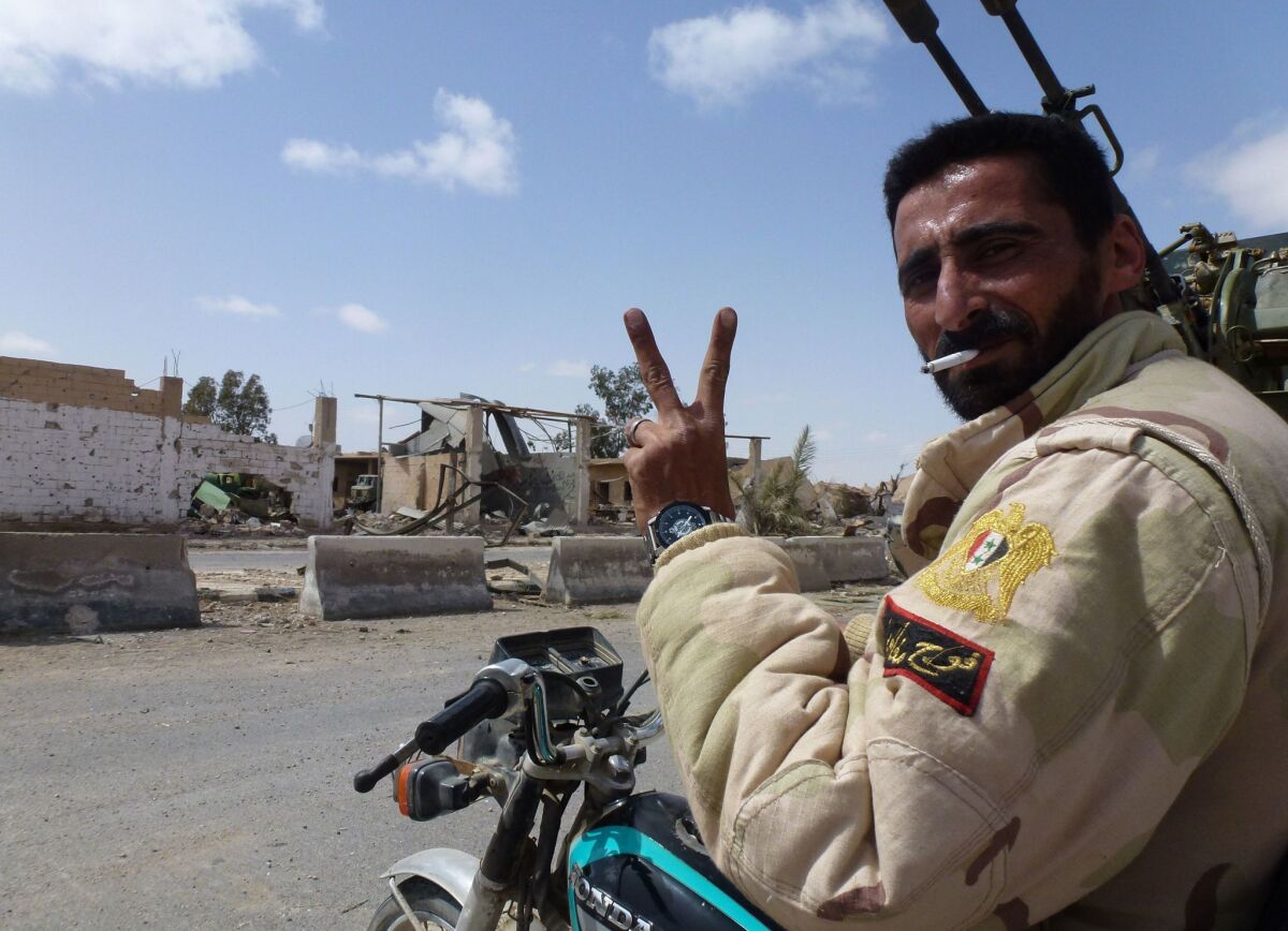 A member of the Syrian pro-government forces flashes the victory sign in a residential neighborhood of Palmyra, after troops recaptured the city from Islamic State.