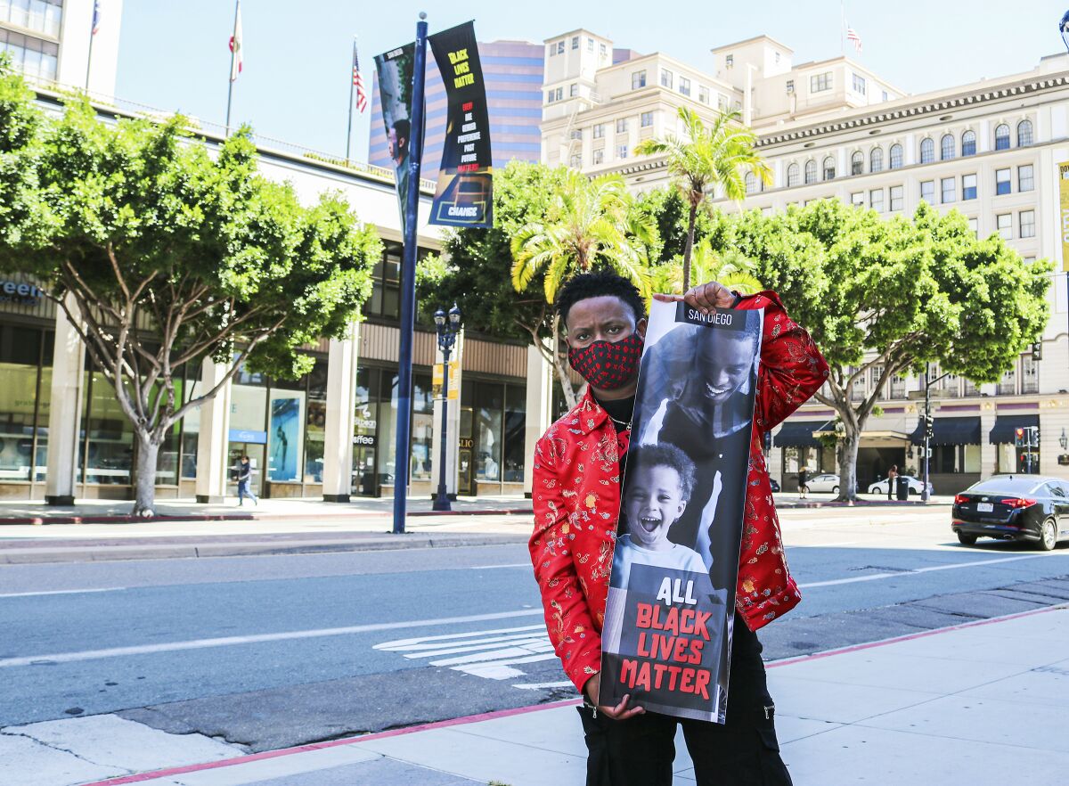 San Diego artist Anthony Tyson holds one of the banners he designed to showcase support for the Black Lives Matter movement