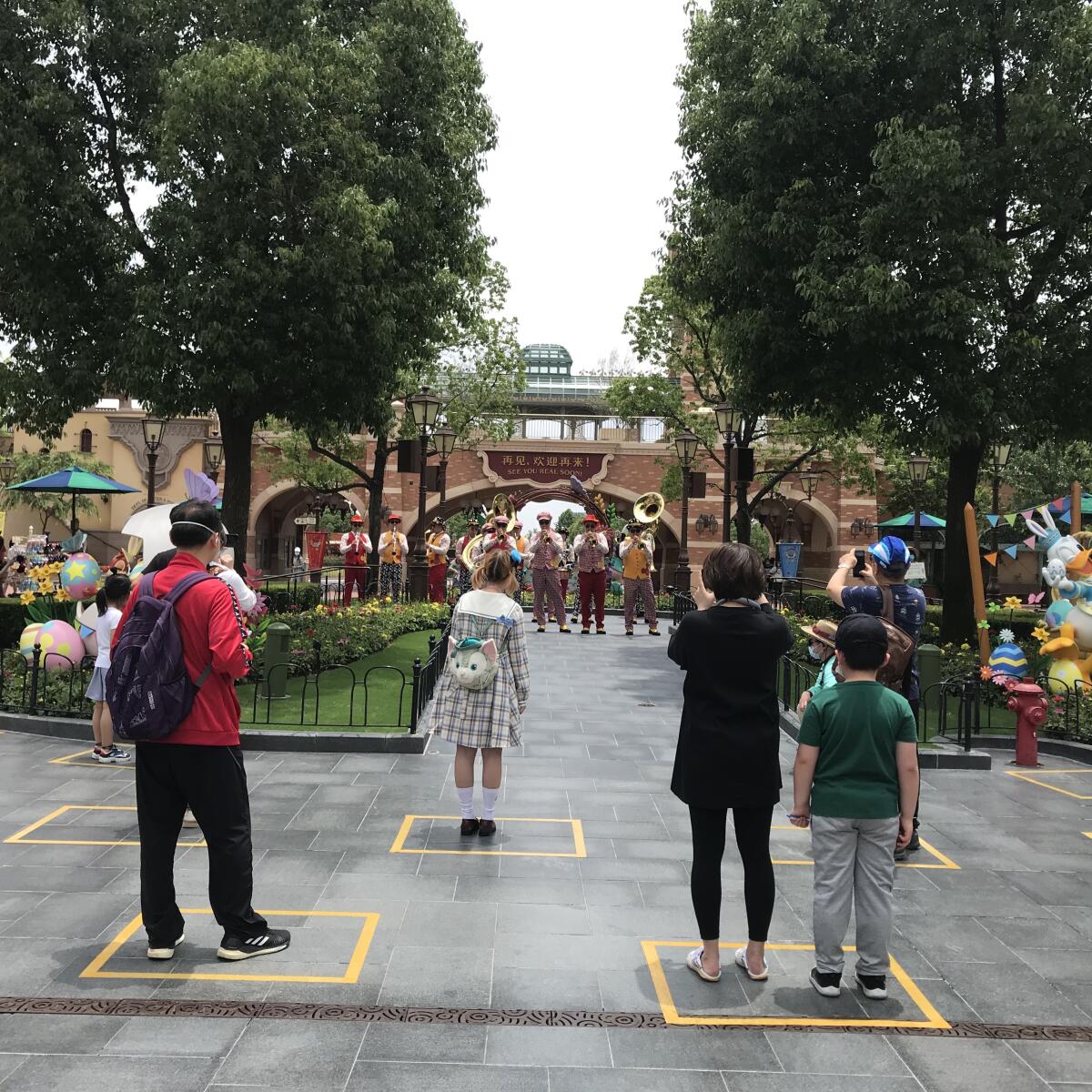 Yellow boxes are taped on the ground to maintain social distancing among visitors inside the park. One family is allowed to stand in each box.
