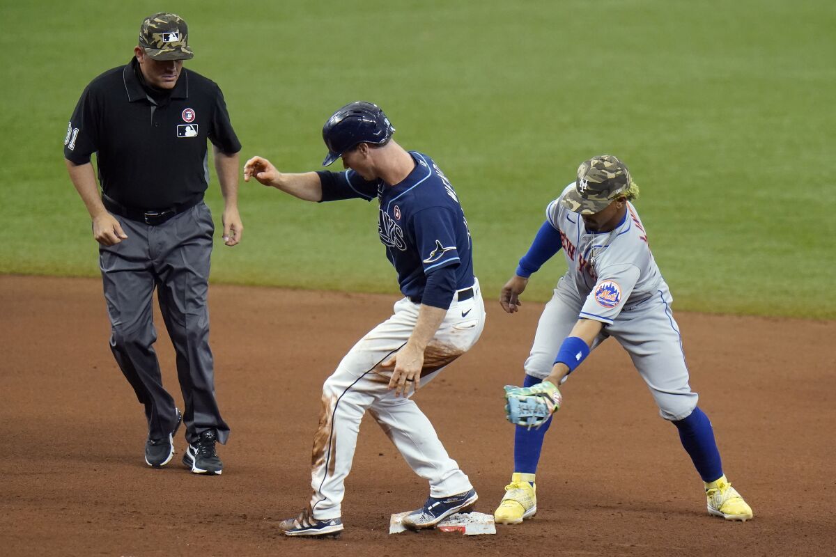 Tampa Bay Rays' Joey Wendle, center reaches second base with a double ahead of the tag by New York Mets shortstop Francisco Lindor, right, during the seventh inning of a baseball game Saturday, May 15, 2021, in St. Petersburg, Fla. Looking on is umpire Brian Knight(AP Photo/Chris O'Meara)