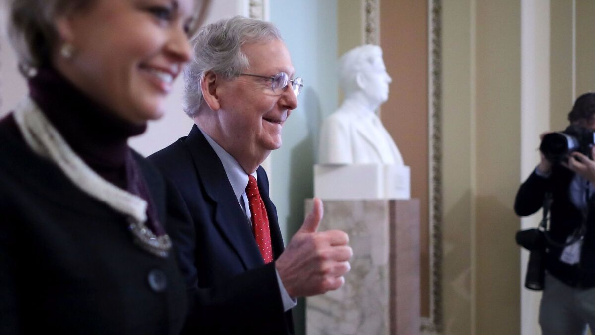 Senate Majority Leader Mitch McConnell (R-KY) gives a thumbs-up as he and his Director of Operations Stephanie Muchow head for the Senate floor in Washington on Dec. 1.
