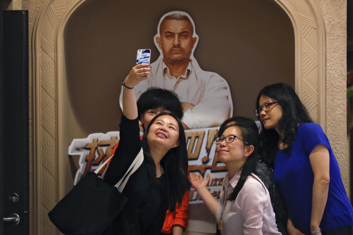 Chinese women take a selfie with a poster of the Indian Bollywood blockbuster "Dangal" at a cinema in Beijing in 2017.