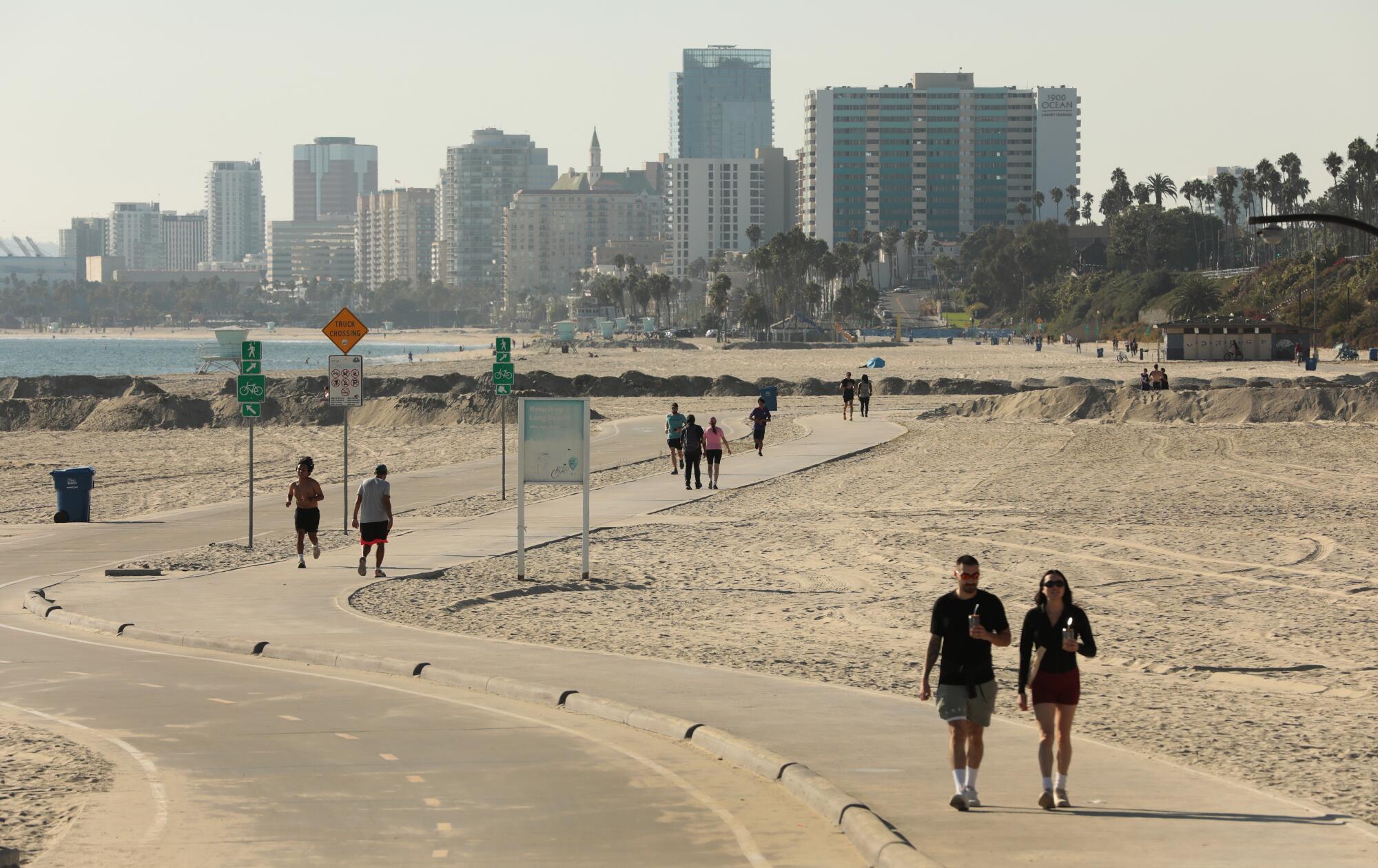 La piste cyclable et piétonne sur la plage de Long Beach, avec l'horizon du centre-ville derrière.