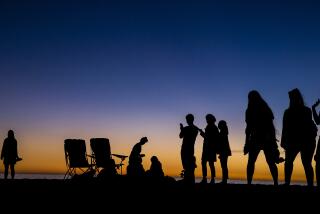 Beachgoers are cast in silhouette after the last rays of sunlight escape into the night on Santa Monica Beach on Wednesday.