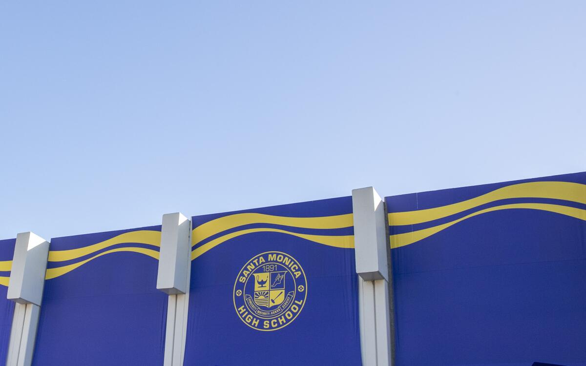A wall with a blue and gold mural and the Santa Monica High School seal