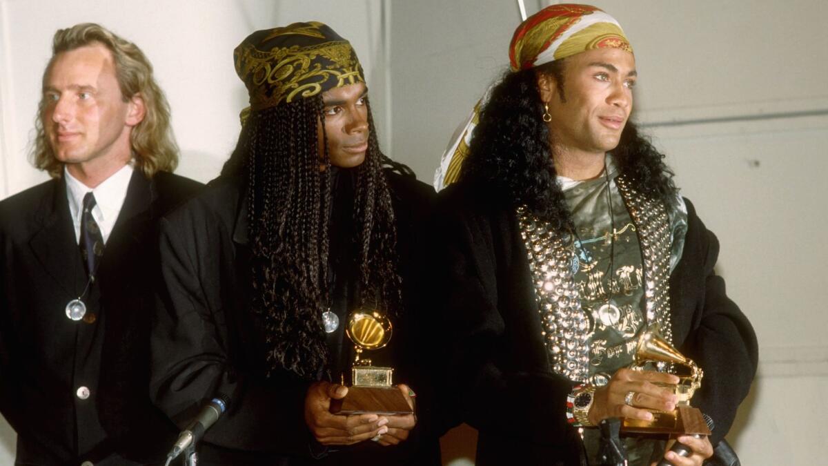 Fabrice "Fab" Morvan, center, and Rob Pilatus, right, hold the Grammys they won in 1990 for best new artists and later returned after admitting they were not the real singers of Milli Vanilli. Their German producer Frank Farian, left, was the man behind the scam.
