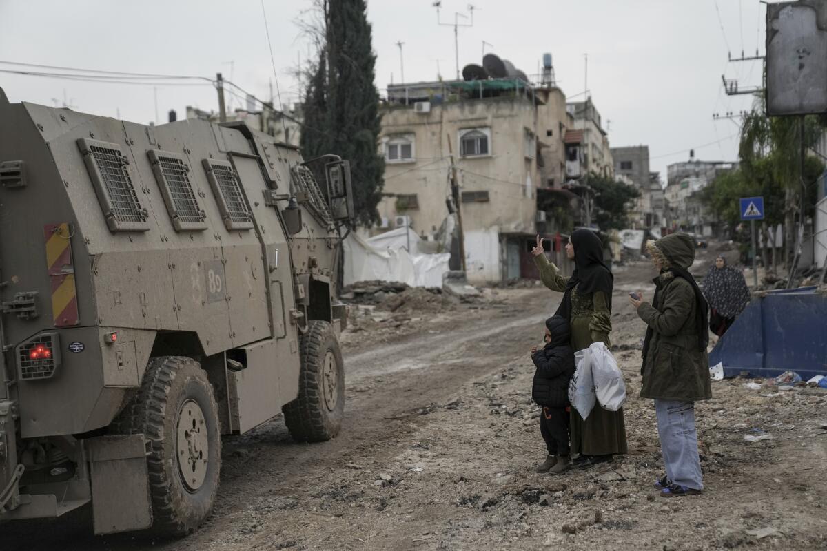 Palestinian woman gesturing at Israeli troops during a raid of a West Bank refugee camp