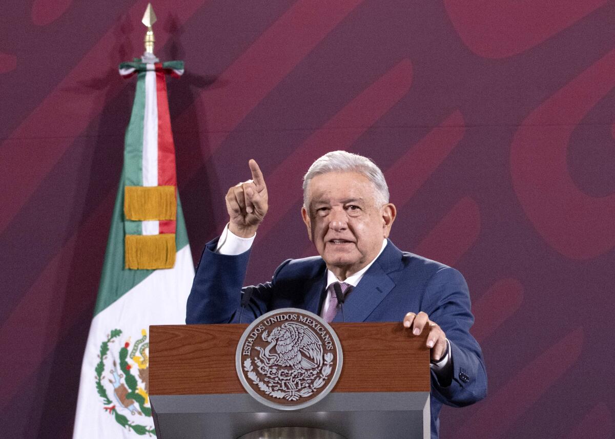 Mexican President Andrés Manuel López Obrador, with his finger pointing upward, gives a lecture from behind a lectern