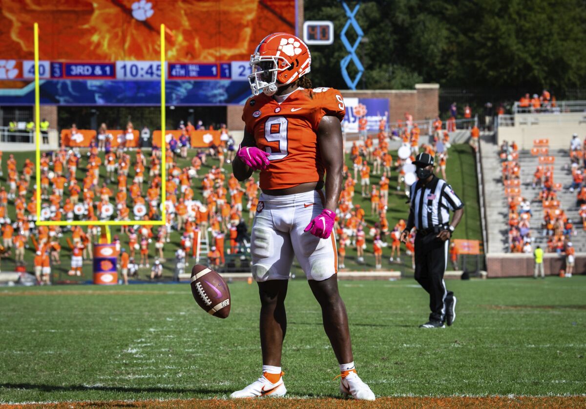 FILE - In this Oct. 24, 2020, file photo, Clemson running back Travis Etienne (9) spins the ball out of his hands after scoring a touchdown during an NCAA college football game against Syracuse in Clemson, S.C. The defense for No. 4 Notre Dame has been solid all season during a 6-0 start. It is about to face its biggest challenge. The Fighting Irish will host top-ranked Clemson on Saturday. The Tigers will be without star quarterback Trevor Lawrence. The Tigers have top running back Travis Etienne. (Ken Ruinard/Pool Photo via AP, File)