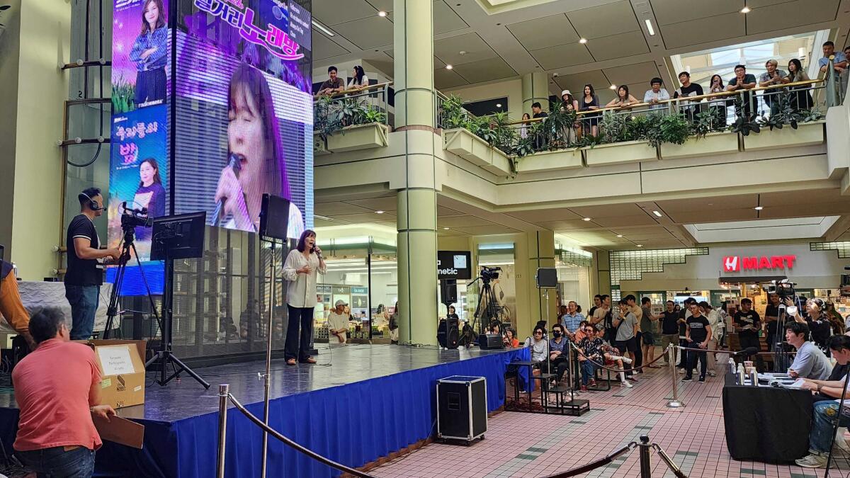 A woman performs at a karaoke competition in a mall.