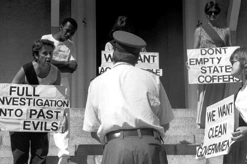 A policeman responds to members of the Black Sash anti-apartheid organization protesting in January 1993 in Cape Town before the opening of Parliament. President Frederik W. de Klerk warned at the time that the country faced civil war if negotiations between the white-minority government and the black majority failed. Pressure was also placed on the government by sanctions and disapproval from other nations.