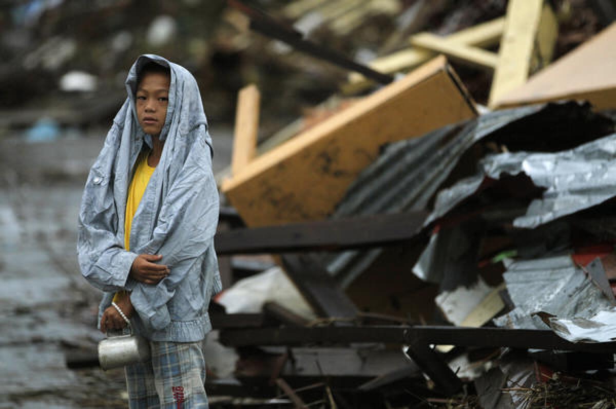 A boy waits at the side of the road for fresh water while near debris from Typhoon Haiyan in Tacloban, central Philippines. U.S. cable operators will offer the Filipino Channel to digital subscribers at no additional charge through Nov. 15.