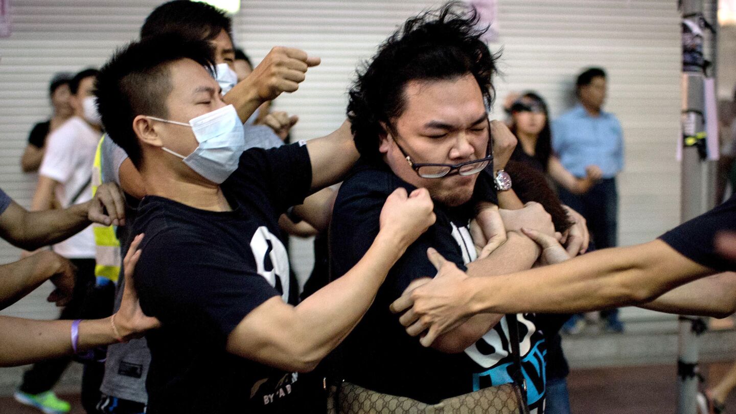 A group of men in masks rough up a man, right, who tried to stop them from removing barricades from a pro-democracy protest area in the Causeway Bay district of Hong Kong on Friday.