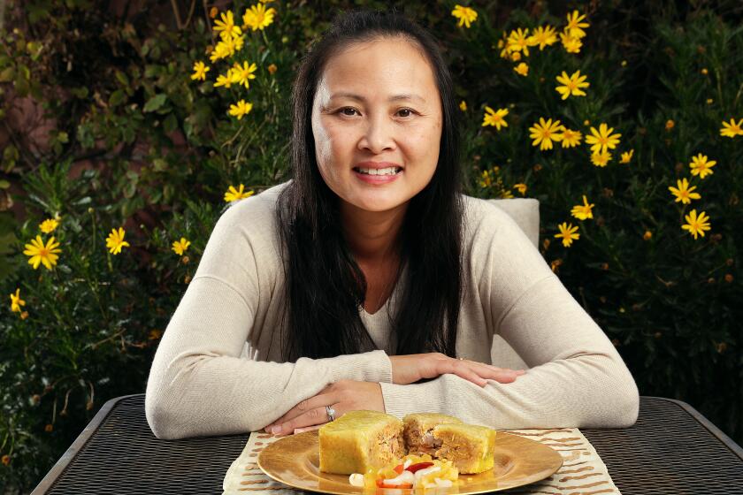 WESTMINSTER-CA-FEBRUARY 1, 2021: Kim Xuyen Ngo is photographed at home in Westminster with a dish of Banh Chung-a delicacy for the Lunar New Year-made of pork belly, mung bean and sticky rice, wrapped in banana leaf, and a side of Dua Mon-dried vegetables soaked in fish sauce, on Monday, February 1, 2021. (Christina House / Los Angeles Times)