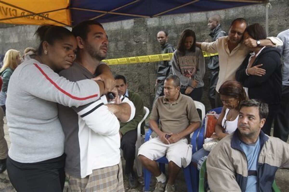 People wait for information after homes were buried by a landslide in the Morro do Bumba area of the Niteroi neighborhood in Rio de Janeiro, Thursday, April 8, 2010. At least 200 people were buried and feared dead under the latest landslide to hit a slum in Rio de Janeiro's metropolitan area, authorities said Thursday. (AP Photo/Silvia Izquierdo)