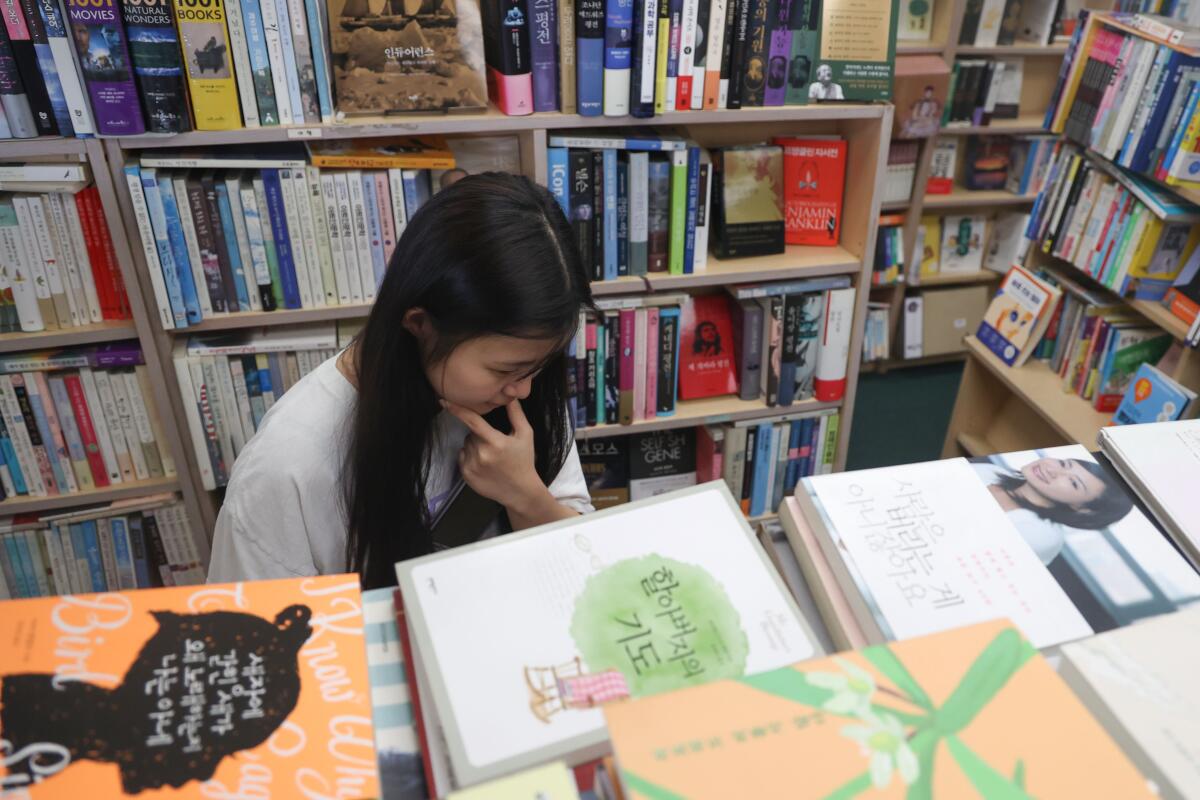 Janet Lee, 18, looks for a book at the Aladdin Fullerton bookstore.