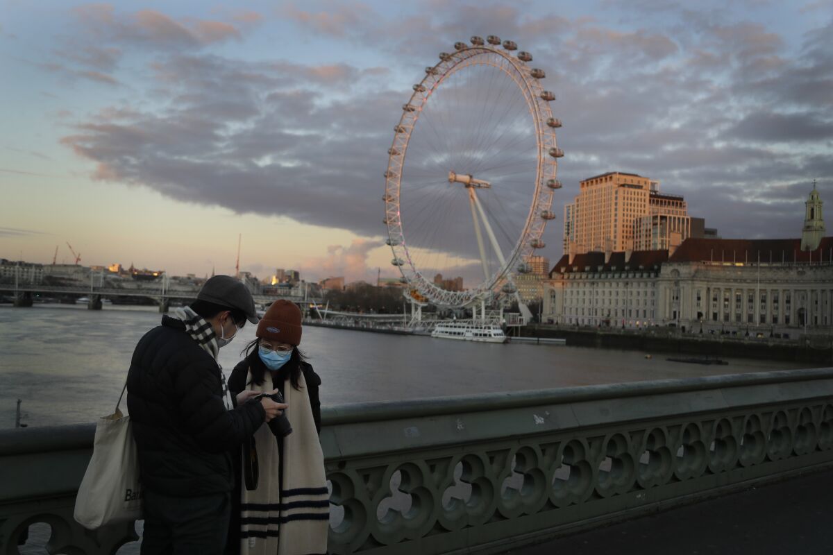 A couple stand on Westminster Bridge as the sun sets in London, Wednesday, Jan. 6, 2021. Britain's Prime Minister Boris Johnson has ordered a new national lockdown for England which means people will only be able to leave their homes for limited reasons, with measures expected to stay in place until mid-February. (AP Photo/Kirsty Wigglesworth)