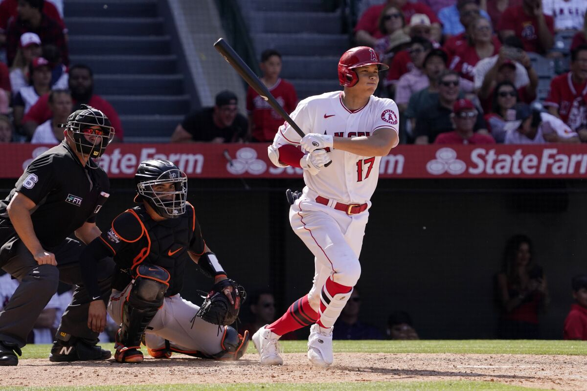 Angels' Shohei Ohtani hits a single as Baltimore Orioles catcher Robinson Chirinos and home plate umpire Mark Carlson watch.